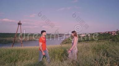 男孩和女孩走到一起，在框架的中心，亲吻，桥，河，树，草，自然，对抗